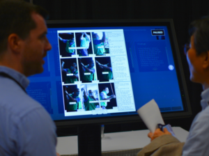 AERA annual meeting presentations sessions: Close-up of an i-Presentation Screen with a table showing research results. In front of the screen we can see the silhouettes of two persons viewing the data.