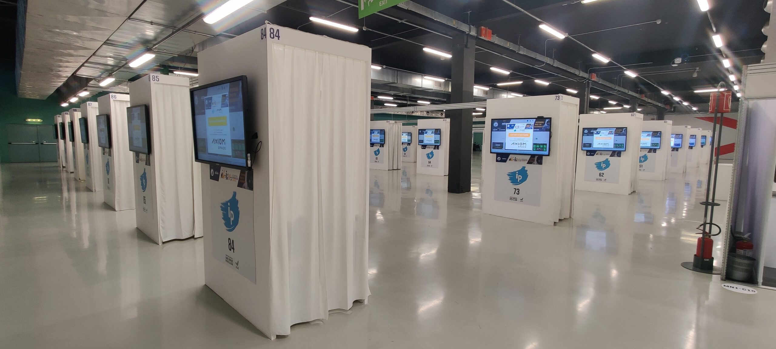 The iPoster Hall at the 2024 IAC "Responsible Space for Sustainability" Congress, in Milan, Italy. The Hall is empty of people. We see rows and rows of large white touch screen kiosks.