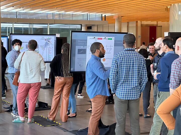 poster sessions in action at the Hanna Gray Meeting. crowd of people milling around standing touch screens that are displaying the iPosters created for the event. 