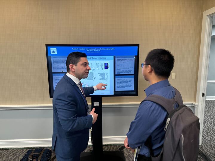 2 people standing infront of a touch screen with an iPoster displayed on it at the 2023 V Summit