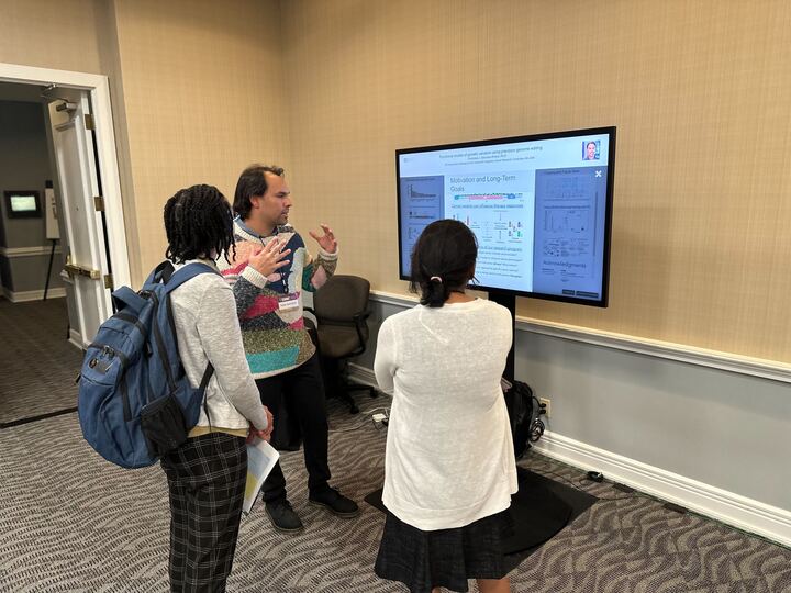 3 people standing around a touch screen with an iPoster displayed on it at the 2023 V Summit