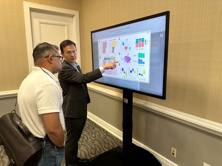 2 people viewing a touch screen with an iPoster displayed on it at the 2023 V Summit