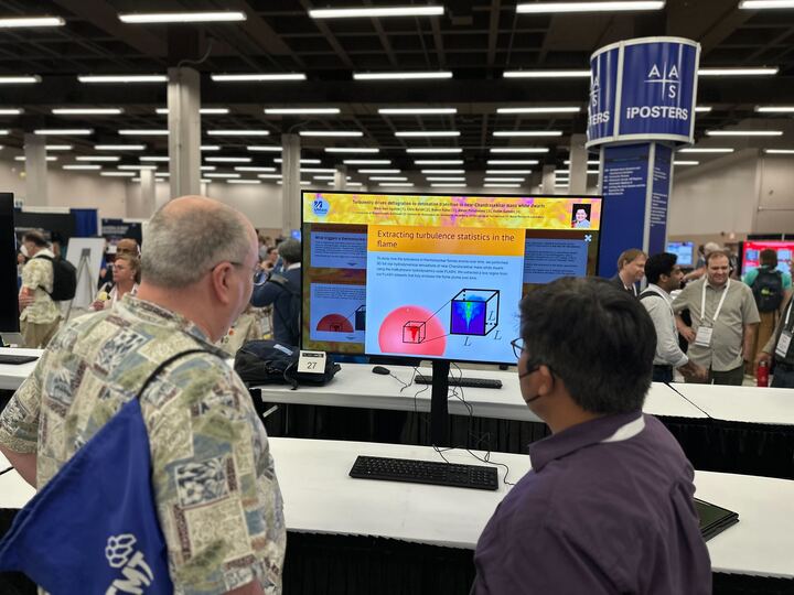 A presenter and an attendee interacting with an iPoster at AAS 242. 